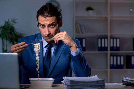 Hungry employee working late in the officeの写真素材