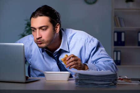 Hungry employee working late in the officeの写真素材