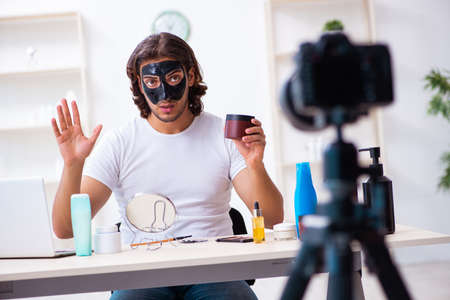 Young male cosmetician recording video for his blogの写真素材