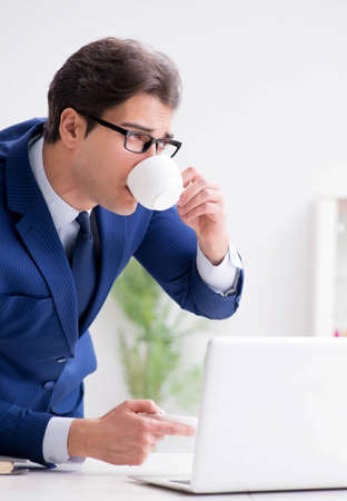 Young handsome businessman drinking coffee in the officeの写真素材