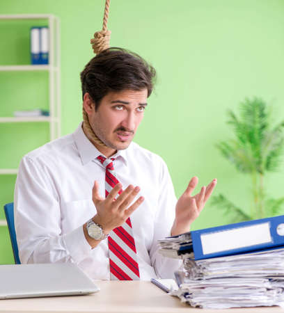 Despaired businessman thinking of suicide in the officeの写真素材