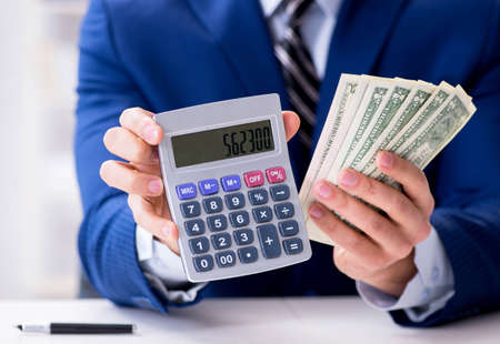 Accountant calculating dollars with calculator in officeの写真素材