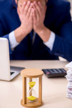 Young male employee in time management conceptの写真素材