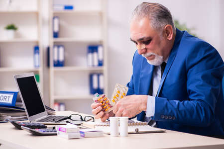Old face injured employee sitting in the officeの写真素材