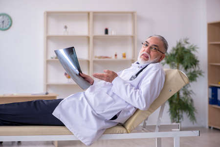 Old male doctor working in the clinicの写真素材