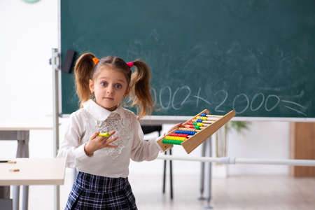 Small girl in front of blackboard in the classroomの写真素材