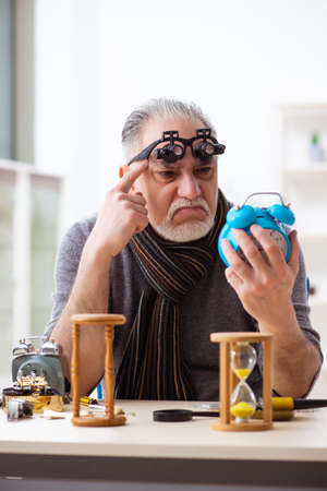 Old male watchmaker working in the workshop