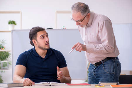 Old teacher and young male student in the classroom