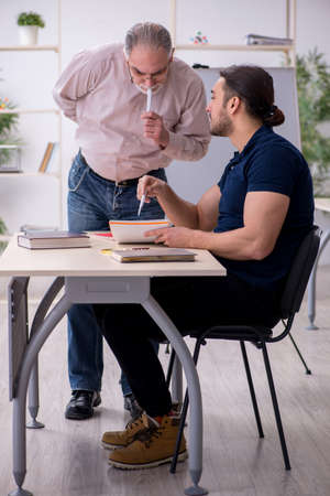 Old teacher and young male student in the classroomの写真素材