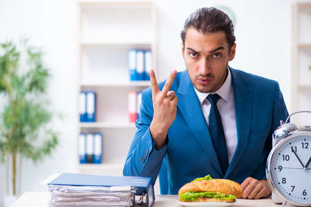 Young male employee having breakfast at workplaceの写真素材