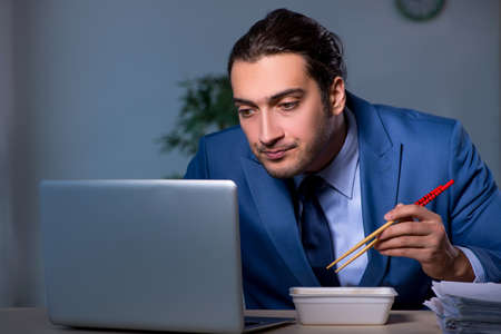 Hungry employee working late in the officeの写真素材