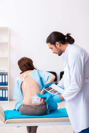 Injured young woman visiting young male doctorの写真素材