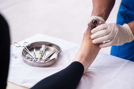 Finger injured woman visiting male doctor traumatologistの写真素材