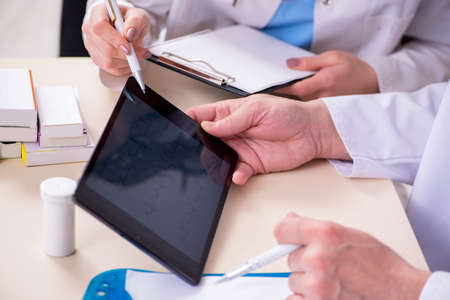 Old male doctor and his young female assistant in the clinicの写真素材