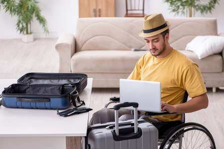 Young man in wheel-chair preparing for departure at homeの写真素材