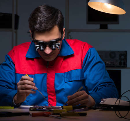 Computer specialist repairing PC late at night