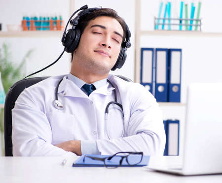 Happy excited doctor listening to music during lunch break in hoの写真素材