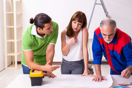 Young couple and old contractor in home renovation concept