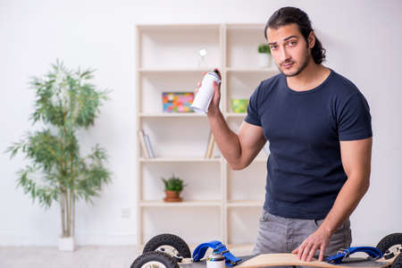 Young male repairman repairing skateboardの写真素材