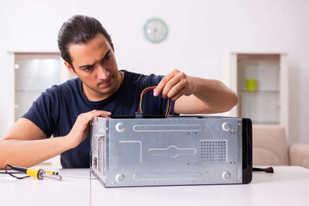 Young man repairing computer at homeの写真素材