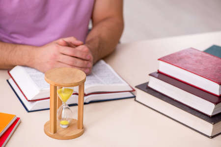 Young male student in the classroom at time management concept