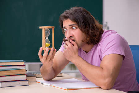 Young male student in the classroom at time management conceptの写真素材