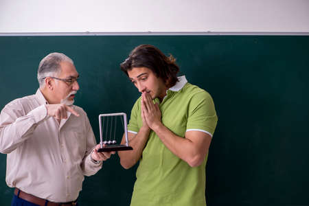 Old professor physicist and young student in the classroom
