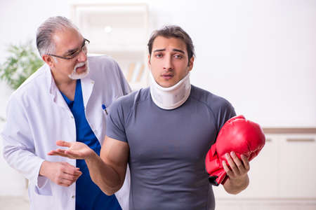 Young injured boxer visiting old doctor traumatologistの写真素材