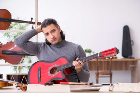 Young male repairman repairing guitarの写真素材
