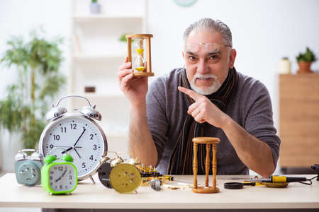 Old male watchmaker working in the workshop