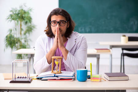 Young male physicist teacher in time management conceptの写真素材