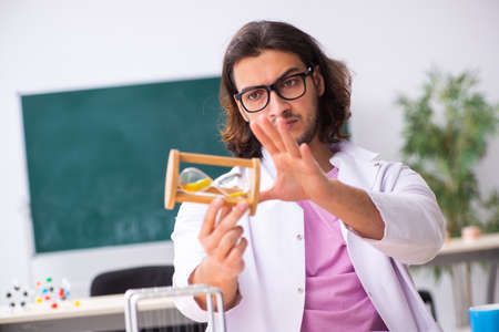 Young male physicist teacher in time management concept