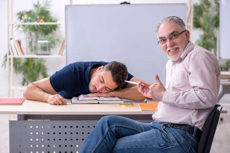 Old teacher and young male student in the classroomの写真素材