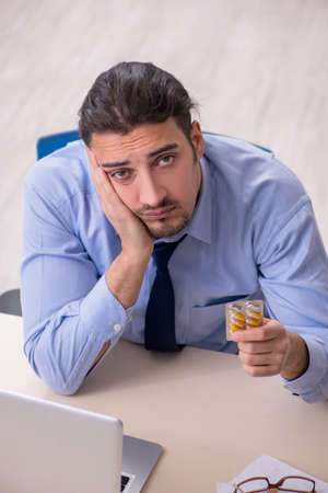 Sick male employee suffering at workplaceの写真素材