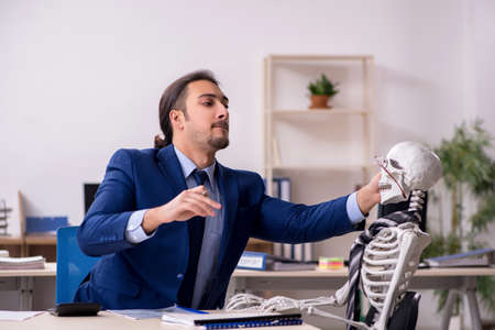 Young male employee with skeletons in the office