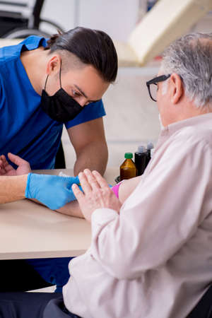 Old patient visiting young male doctor in blood transfusion concの写真素材