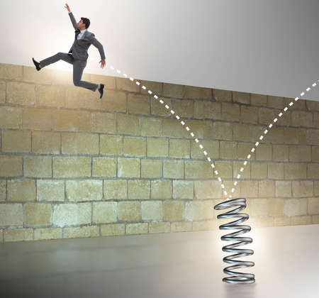 Businessman jumping from spring in business conceptの写真素材