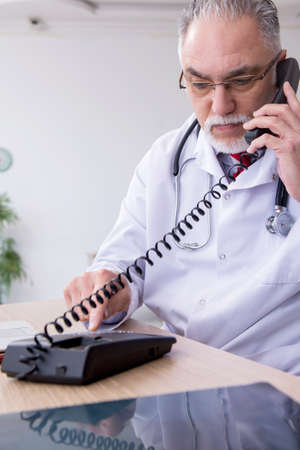 Old male doctor working in the clinicの写真素材