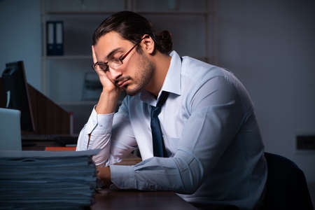 Young male employee working in the office night timeの写真素材