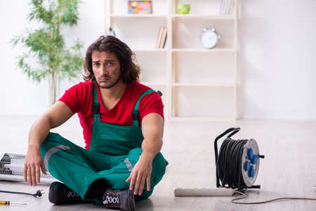 Young male contractor repairing heater indoorsの写真素材