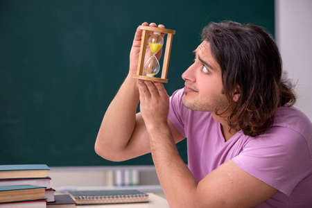 Young male student in the classroom at time management concept