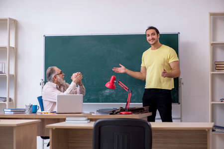 Old teacher and young male student in the classroom