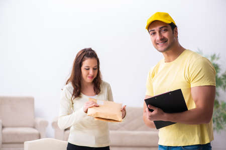 Young male courier delivering parcel to the officeの写真素材
