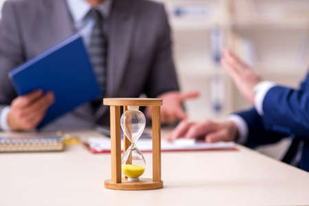 Two businessmen in time management conceptの写真素材