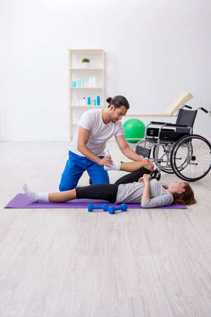 Leg injured woman doing sport exercises with personal coachの写真素材