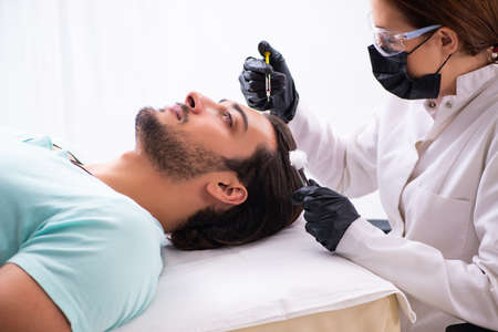 Young man visiting beautician in hair transplantation conceptの写真素材