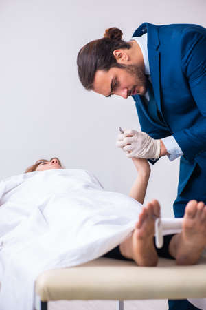 Police coroner examining dead body corpse in morgueの写真素材