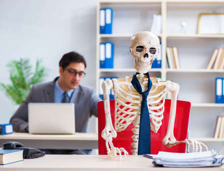 Businessman working with skeleton in officeの写真素材