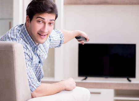 Young man watching tv at homeの写真素材