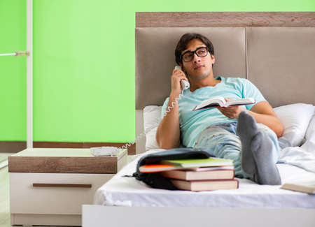 Student preparing for exams at home in bedroom lying on the bedの写真素材